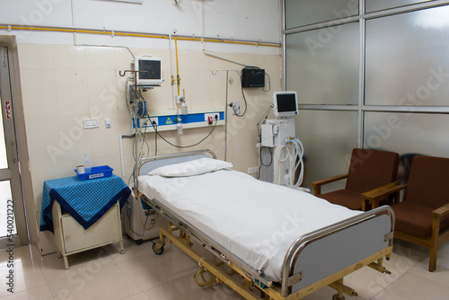Empty ICU room with bed, central oxygen supply, ventilator with infusion pumps.