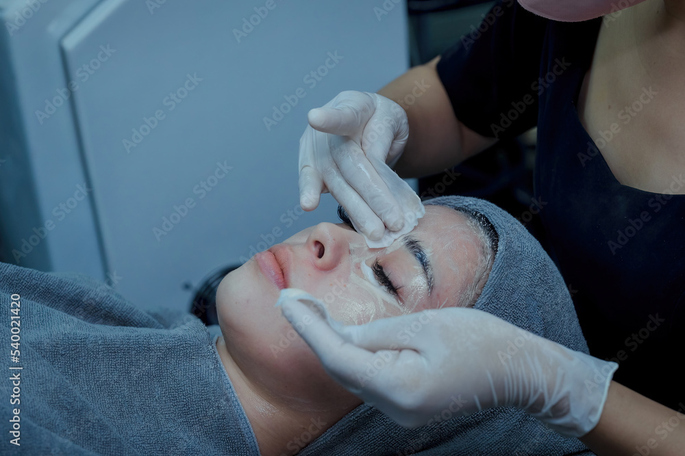 The female dermatologist do face massaged to beautiful girl cosmetology cabinet or beauty clinic. Concept of face cleanser, skin and health care