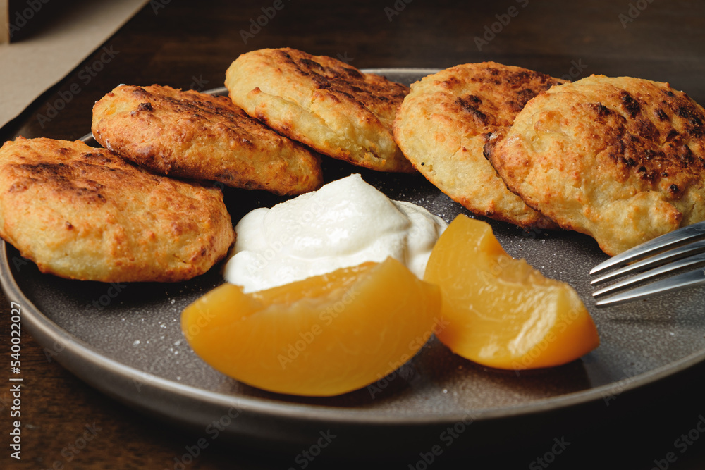 Cottage cheese pancakes,curd fritters with  and apricot slices  and sour cream in a dish. Gourmet Breakfast
