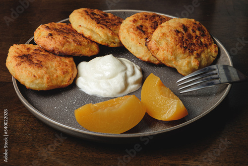 Cottage cheese pancakes,curd fritters with and apricot slices and sour cream in a dish. Gourmet Breakfast 