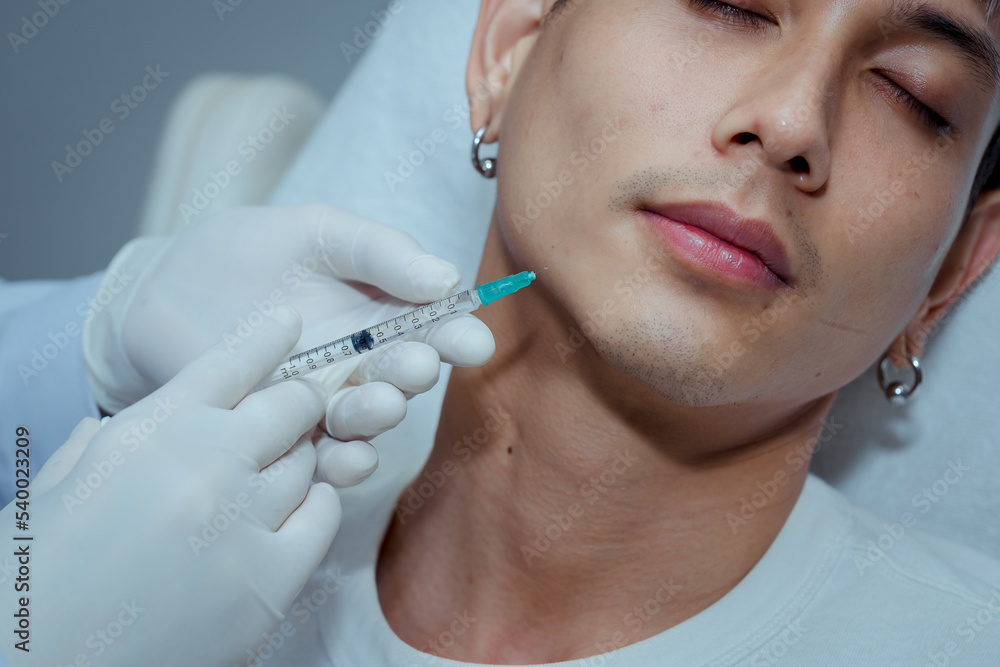 Cosmetologist Doctor makes facial rejuvenation injection procedure for tightening and smoothing wrinkles on face of beautiful young man in beauty skin care salon. , Beauty clinic concepts.