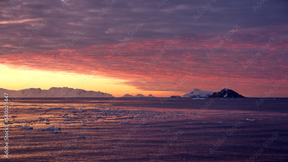 Colorful sunset over mountains and a field of floating icebergs at Cierva Cove, Antarctica