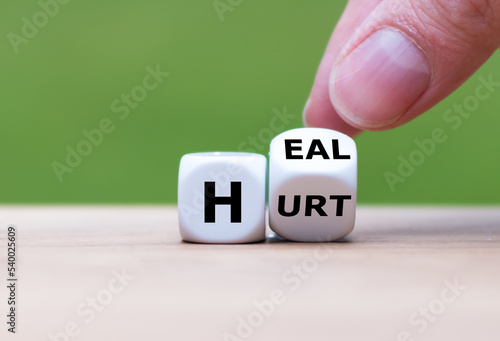 Hand turns dice and changes the word hurt to heal.
