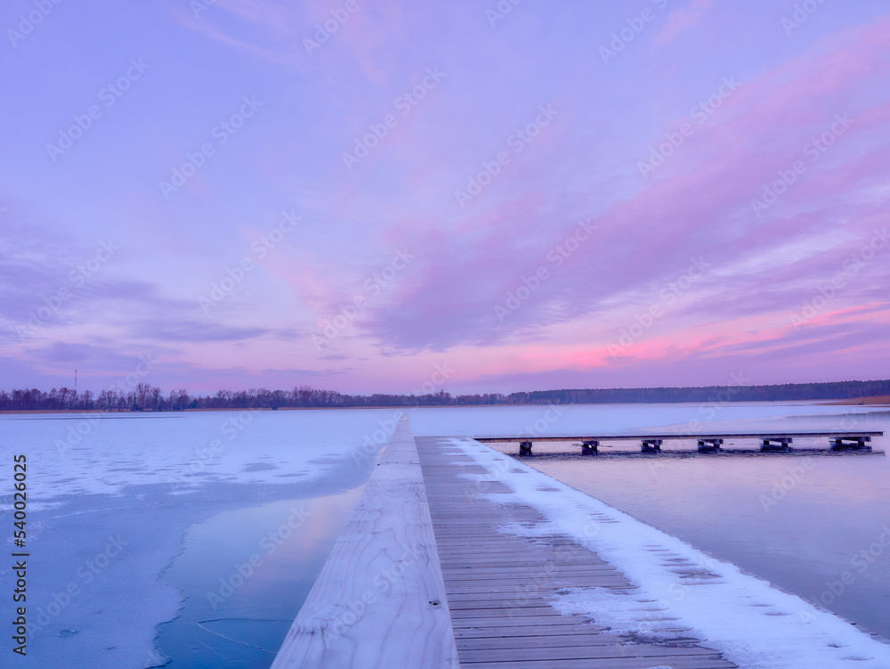 Pier on a frozen lake. Sunset over a frozen lake.