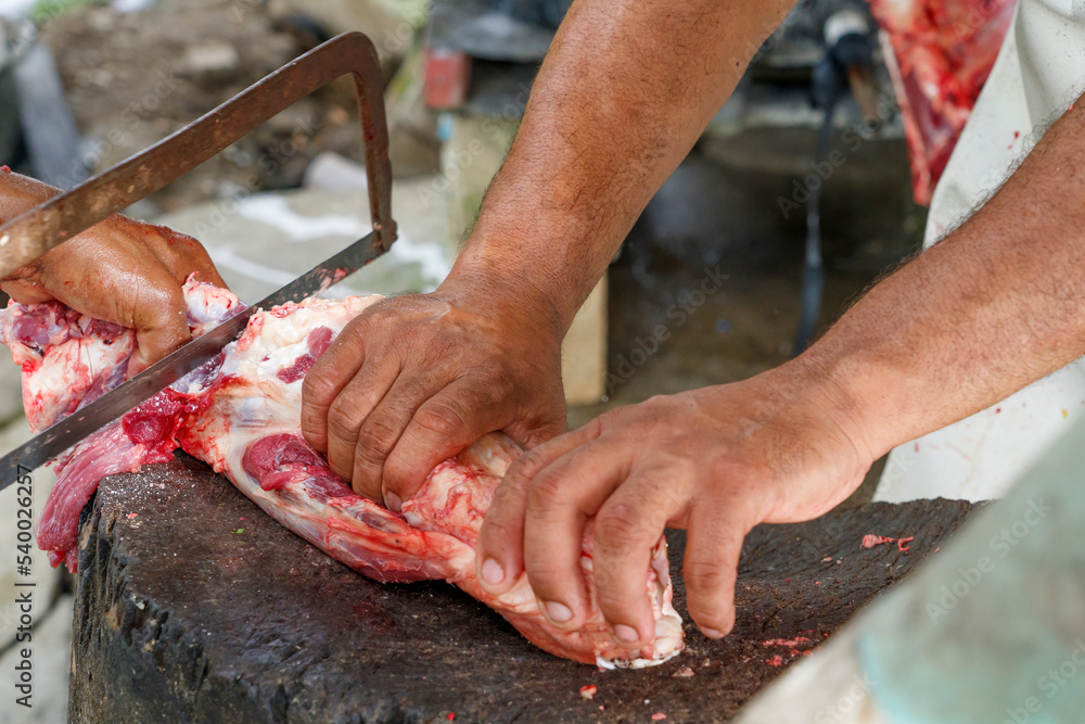 Men in the countryside cut up pieces of beef. Farmers prepare meat for sale.
