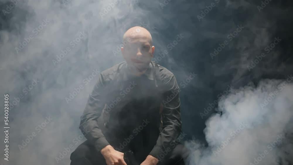 FBI agent holds service pistol gun in his hand and leans forward on camera. Police detective sits on chair. Law enforcement officer. Male cop. Justice. Dark room with smoke FBI agent holds service pistol gun in his hand and leans forward on camera. Police detective sits on chair. Law enforcement officer. Male cop. Justice. Dark room with smoke