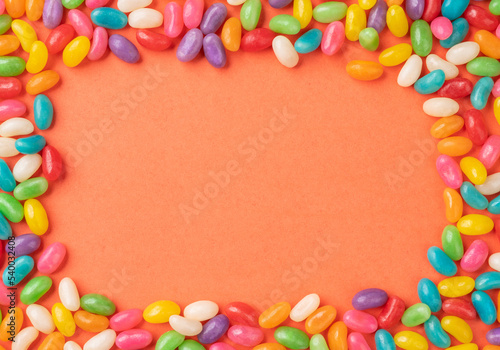 Frame of colorful candies over orange background with copy space