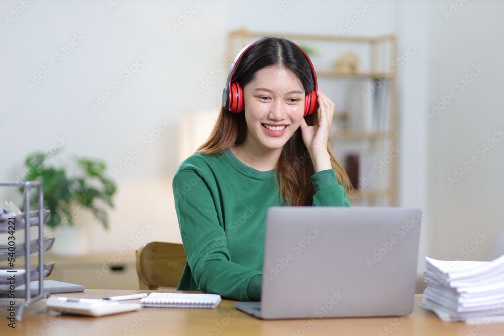 Beautiful Asian woman working on laptop and documents in home office. Beautiful Asian woman working on laptop and documents in home office.