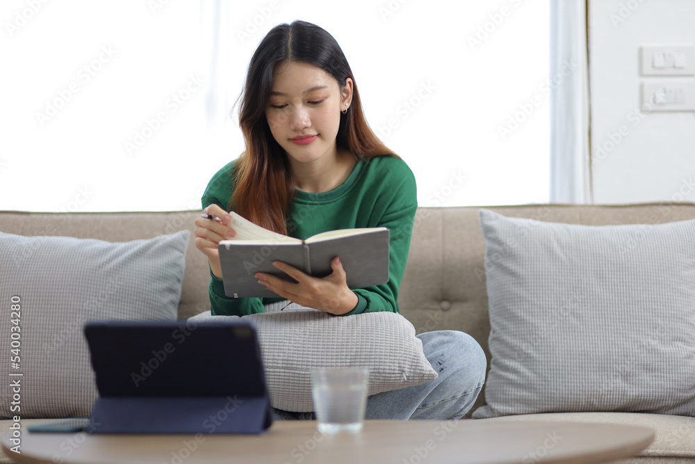 Beautiful asian woman sitting on the sofa reading a book in the house. Beautiful asian woman sitting on the sofa reading a book in the house.