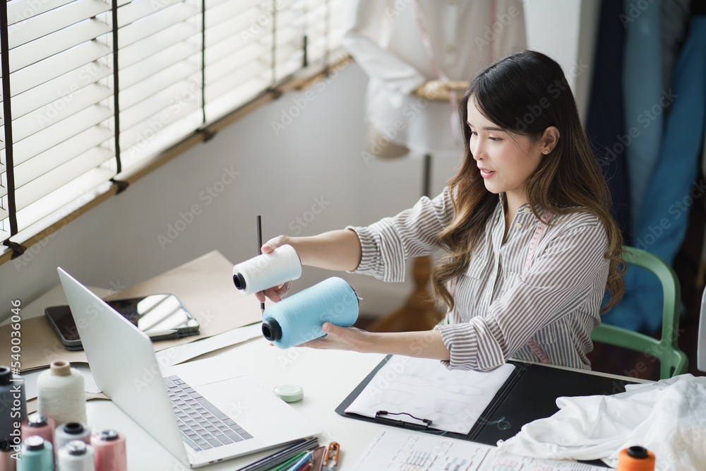 Optimistic Asian young woman made her small business as clothes designer. Lifestyle new generation lady entrepreneur freelancer.