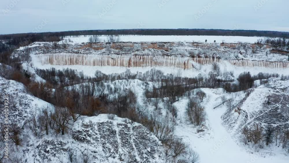 Drone flies over the snowy old chalk quarry, in winter. Beautiful snow-covered winter landscape with hilly terrain. Aerial view of the snowy valley in winter. Beautiful snowy landscape.. Drone flies over the snowy old chalk quarry, in winter. Beautiful snow-covered winter landscape with hilly terrain. Aerial view of the snowy valley in winter. Beautiful snowy landscape..