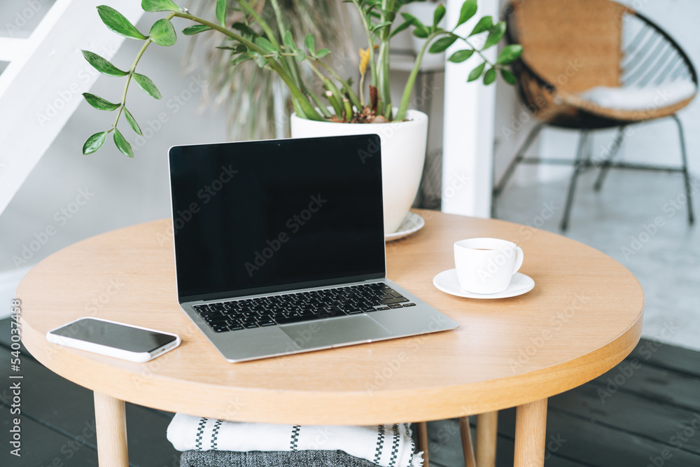 Working place with cup of coffee, open laptop on wooden table in room Working place with cup of coffee, open laptop on wooden table in room