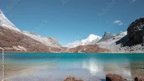 Milk lake with limestone mountain range and tourists travelling on Tibetan plateau in sunny day at Yading nature reserve photo