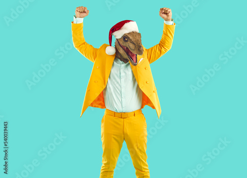 Foto Funny winner man wearing yellow suit, dinosaur mask and Christmas cap standing i