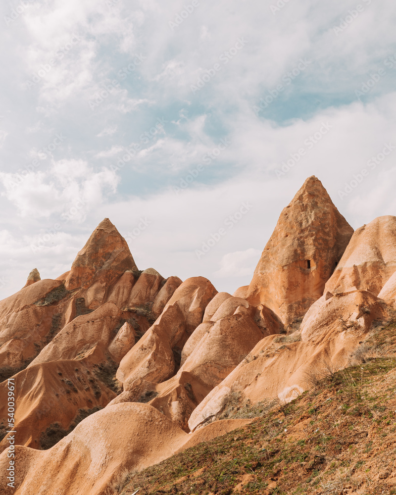Rough rocky formations under cloudy blue sky in sunlight Rough rocky formations under cloudy blue sky in sunlight