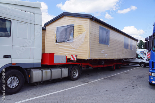 A very long and wide vehicle. Oversized cargo or exceptional convoy. A truck with a special semi-trailer for the transport of oversized cargo - transport of finished houses. © Wlodzimierz