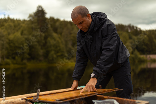 An african american man standing on a raft pointing on a wooden map.