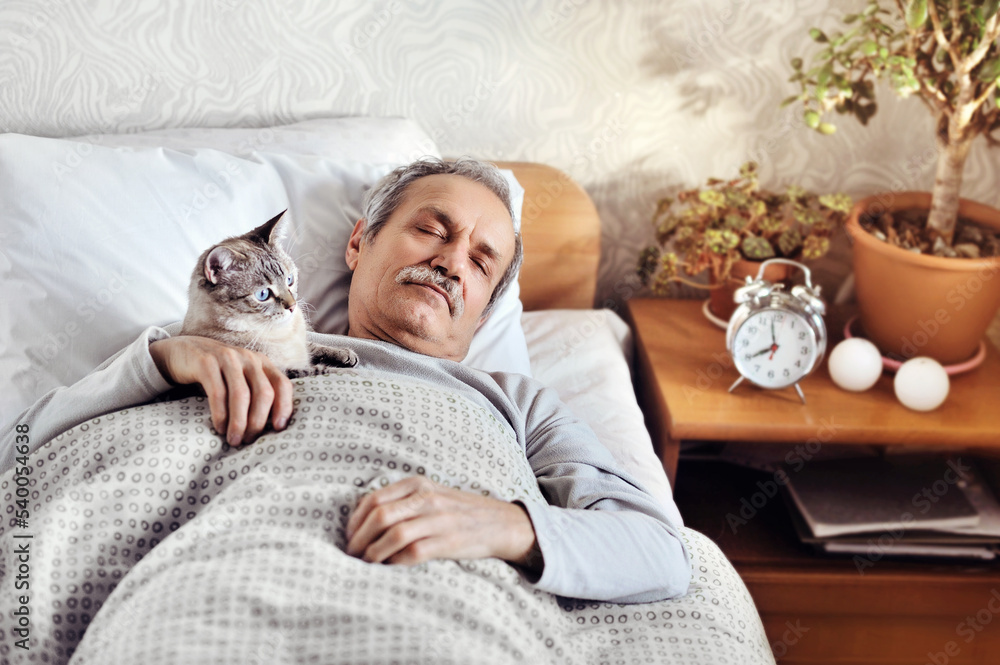 Senior man sleeping in the bed in company of his cat
