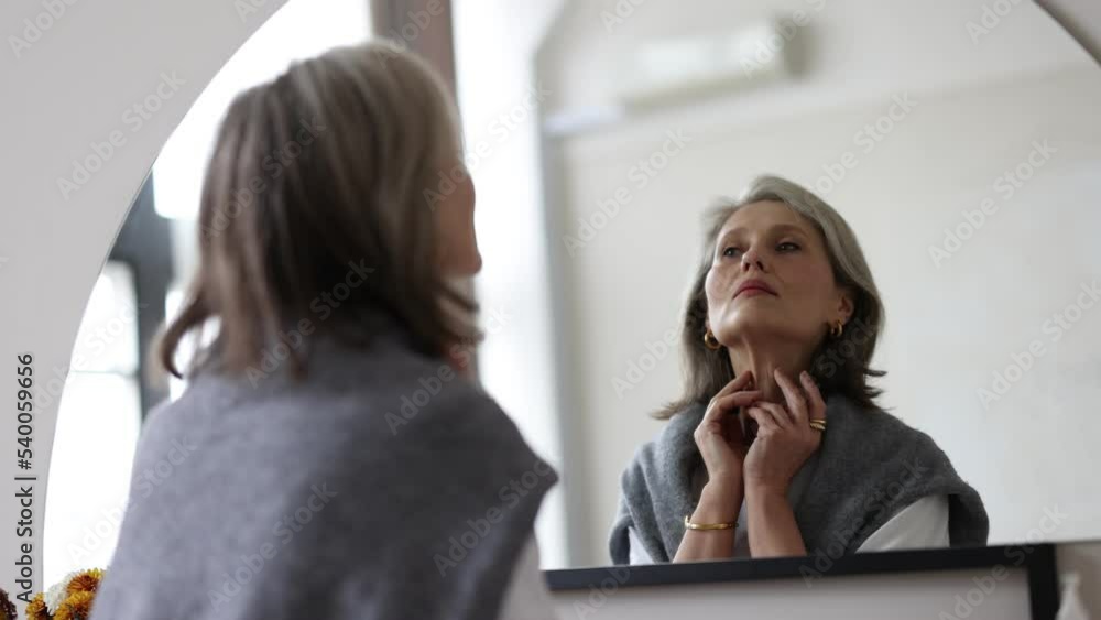 stylish woman of retirement age with a good face in front of a mirror, concept of skin care for a woman in old age stylish woman of retirement age with a good face in front of a mirror, concept of skin care for a woman in old age