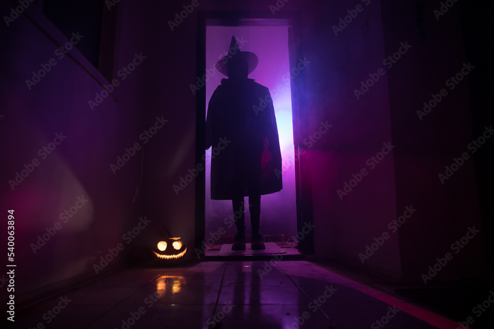 Halloween concept. Creepy silhouette in the dark corridor with pumpkin head. Toned light with fog on background. Halloween concept. Creepy silhouette in the dark corridor with pumpkin head. Toned light with fog on background.