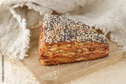 Fresh baked puff lye corner with poppy and sesame seeds closeup on wooden board.