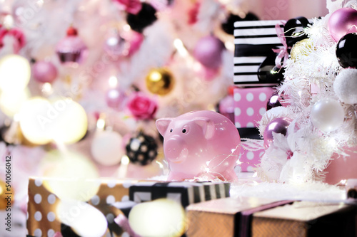 Pink piggy bank against white decorated christmas tree
