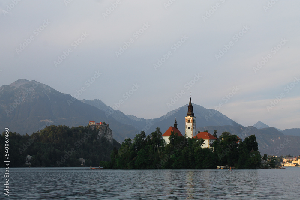 Church in the middle of lake bled in Slovenia at the golden hour with mountains in the background 