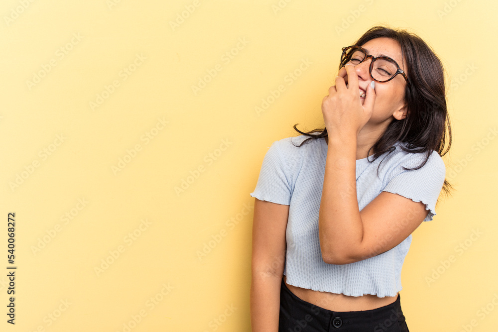 Young Indian woman isolated on yellow background laughing happy, carefree, natural emotion.