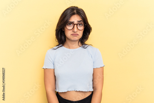 Young Indian woman isolated on yellow background sad, serious face, feeling miserable and displeased.