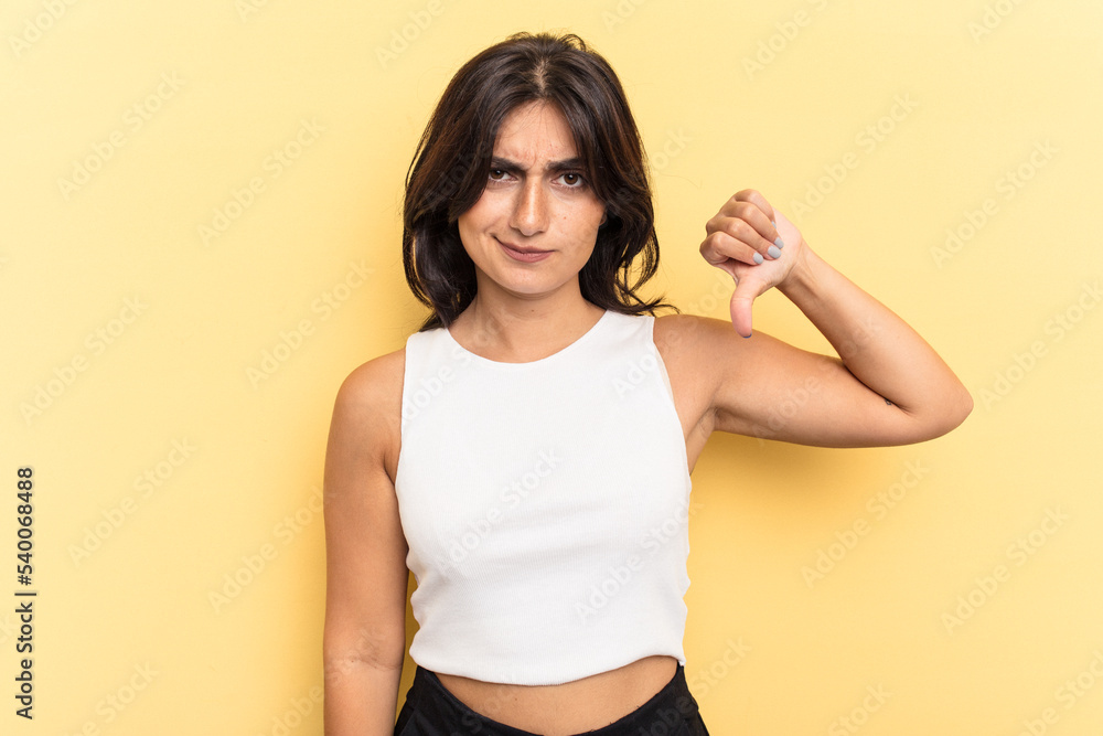 Young Indian woman isolated on yellow background showing thumb down, disappointment concept. Young Indian woman isolated on yellow background showing thumb down, disappointment concept.