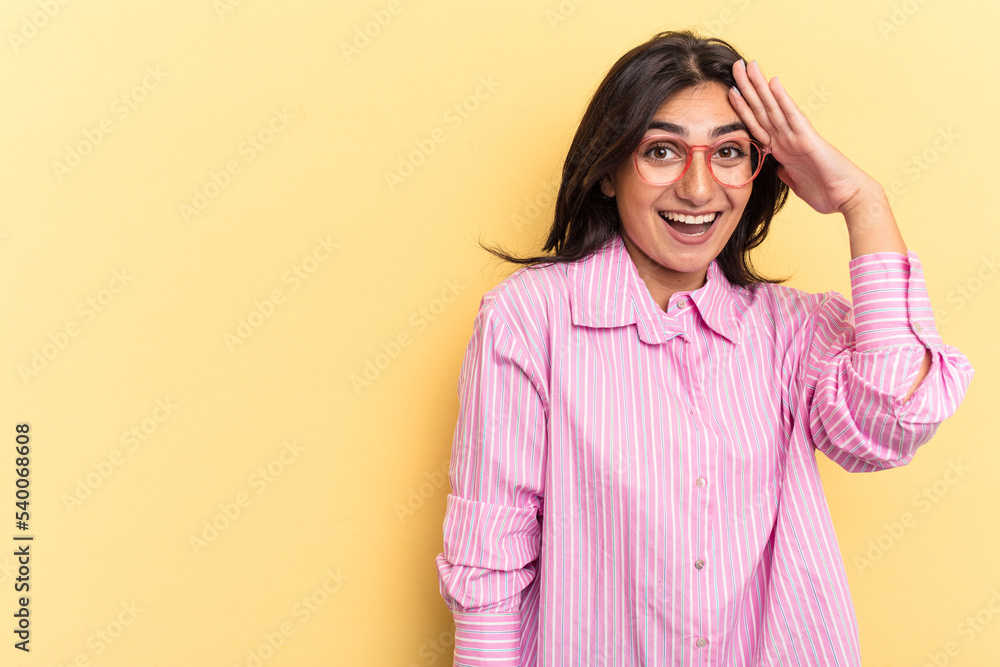 Young Indian woman isolated on yellow background shouts loud, keeps eyes opened and hands tense. Young Indian woman isolated on yellow background shouts loud, keeps eyes opened and hands tense.
