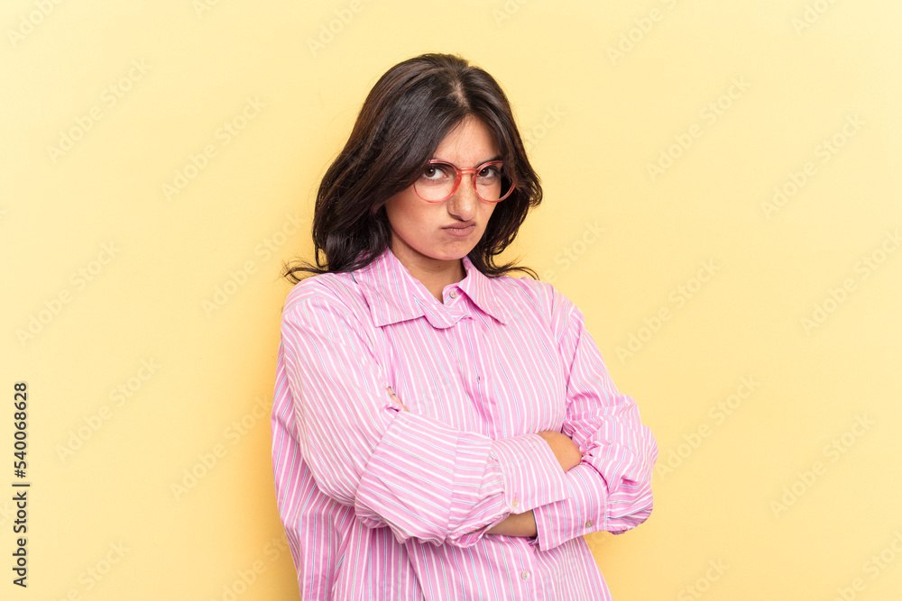 Fototapeta premium Young Indian woman isolated on yellow background frowning face in displeasure, keeps arms folded.