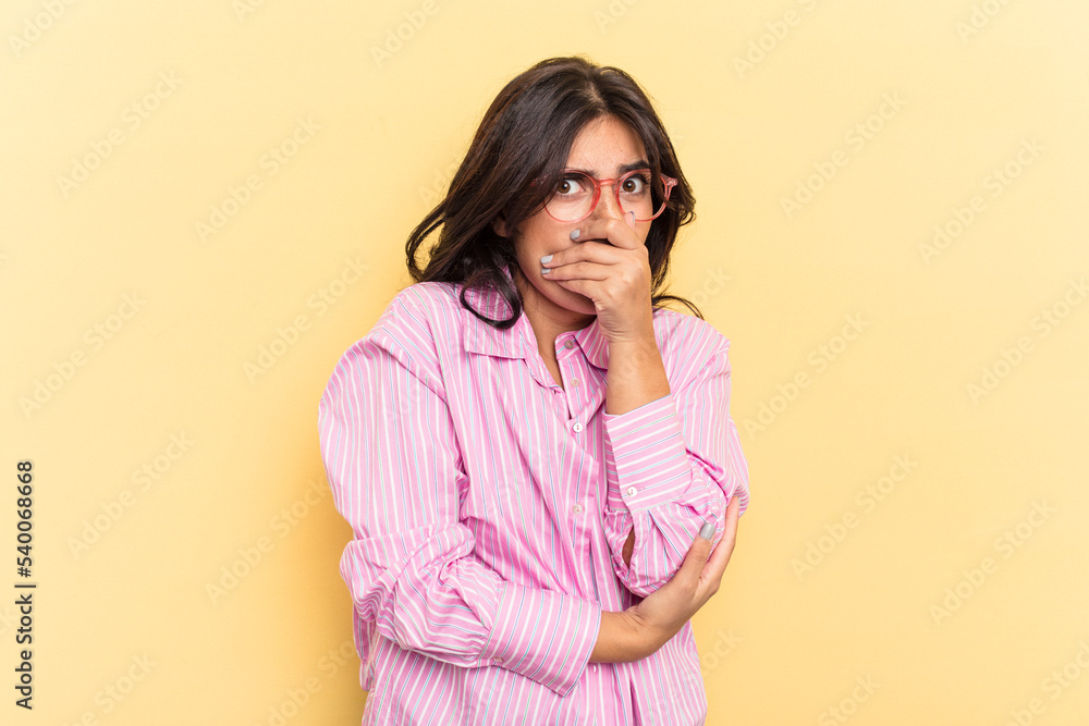 Young Indian woman isolated on yellow background scared and afraid.