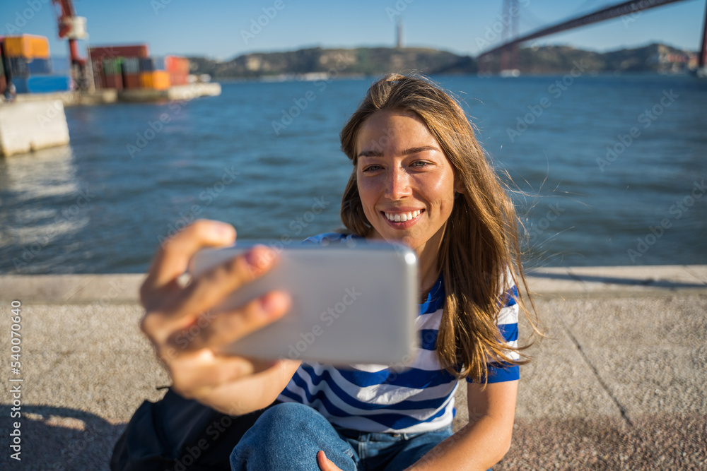 Positive blonde woman making selfie at her mobile device while enjoying