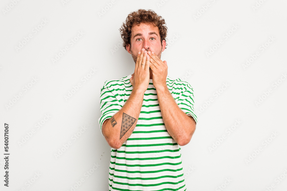 Young caucasian curly hair man isolated on white background shocked, covering mouth with hands, anxious to discover something new. Young caucasian curly hair man isolated on white background shocked, covering mouth with hands, anxious to discover something new.