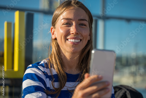 Positive tourist woman using smartphone sitting on the bench at the embankment Free Download Positive tourist woman using smartphone sitting on the bench at the embankment - GFXLoad