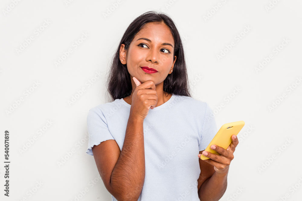 Young indian woman using mobile phone isolated on white background looking sideways with doubtful and skeptical expression. Young indian woman using mobile phone isolated on white background looking sideways with doubtful and skeptical expression.