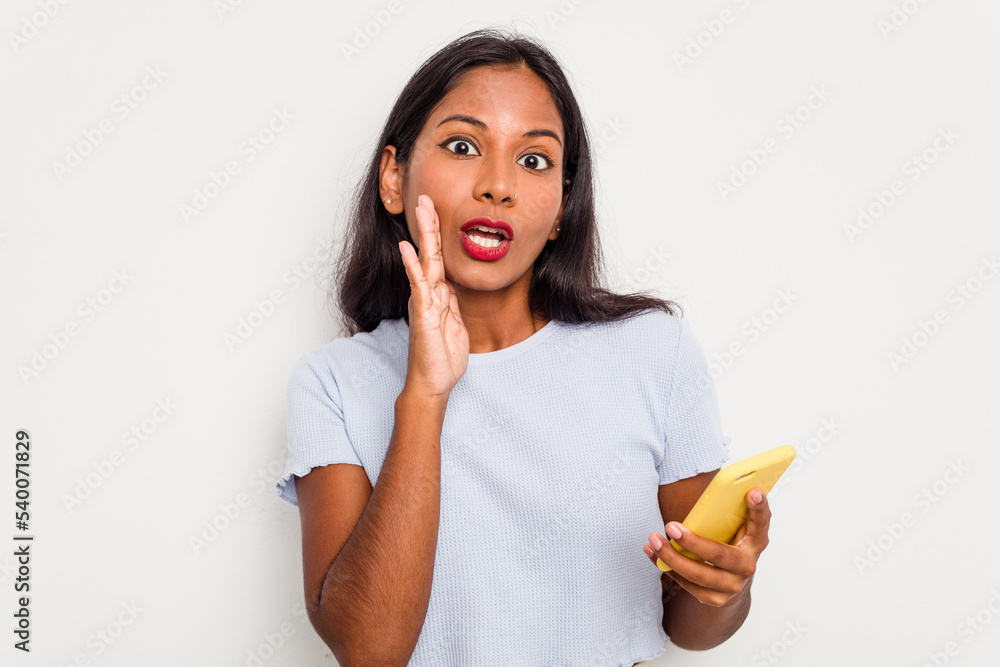 Young indian woman using mobile phone isolated on white background is saying a secret hot braking news and looking aside Young indian woman using mobile phone isolated on white background is saying a secret hot braking news and looking aside