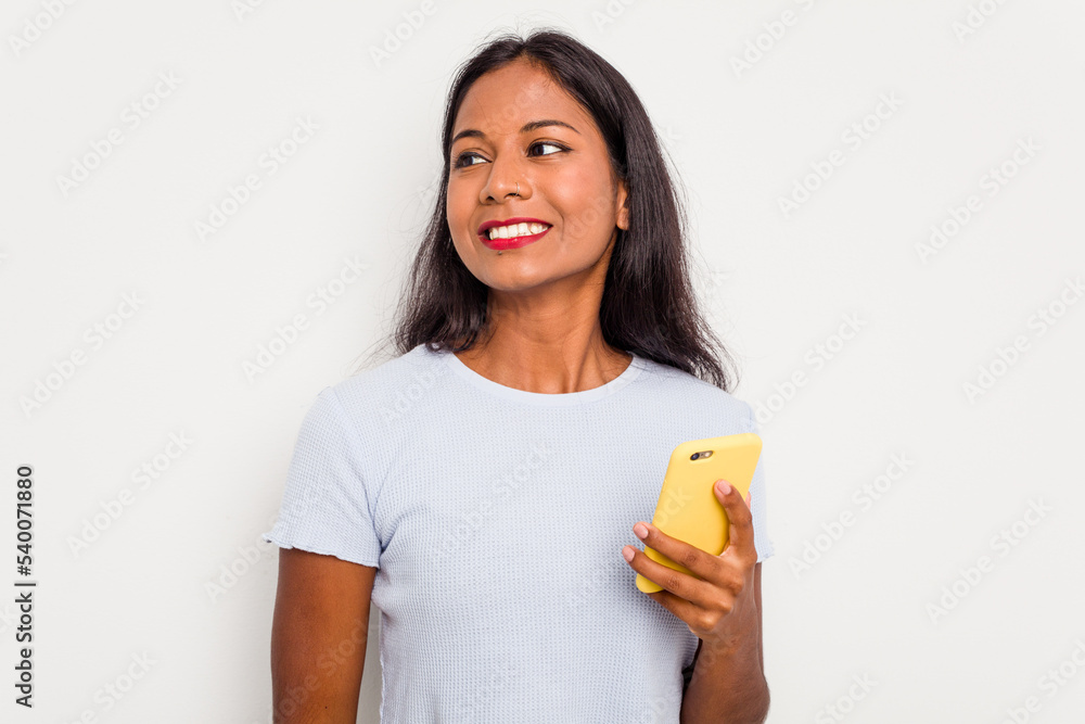 Young indian woman using mobile phone isolated on white background looks aside smiling, cheerful and pleasant. Young indian woman using mobile phone isolated on white background looks aside smiling, cheerful and pleasant.