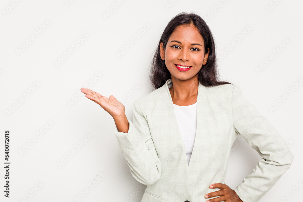 Young business Indian woman isolated on white background showing a copy space on a palm and holding another hand on waist. Young business Indian woman isolated on white background showing a copy space on a palm and holding another hand on waist.