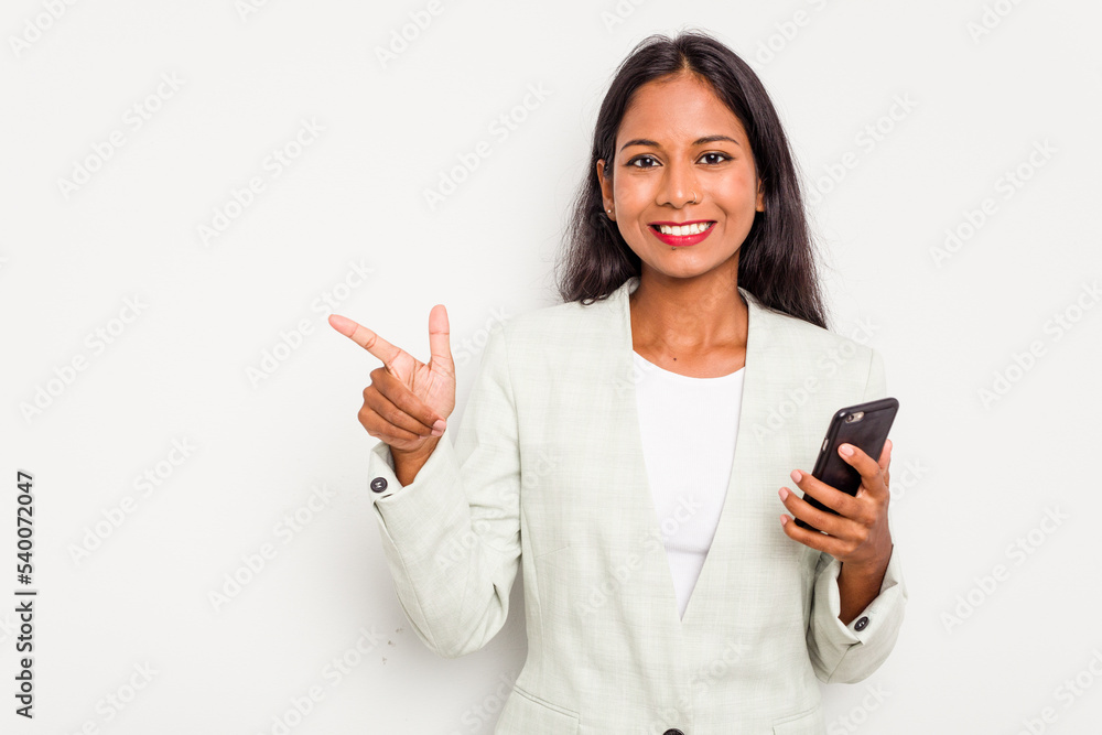 Young business Indian woman holding a mobile phone isolated on white background smiling and pointing aside, showing something at blank space. Young business Indian woman holding a mobile phone isolated on white background smiling and pointing aside, showing something at blank space.