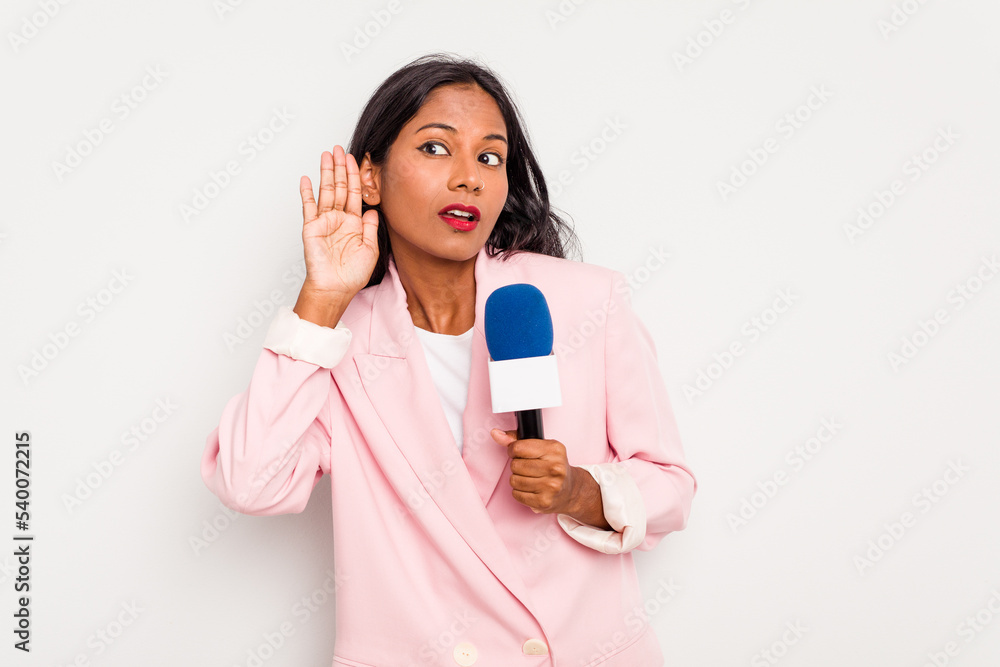 Young TV presenter indian woman isolated on white background trying to listening a gossip. Young TV presenter indian woman isolated on white background trying to listening a gossip.