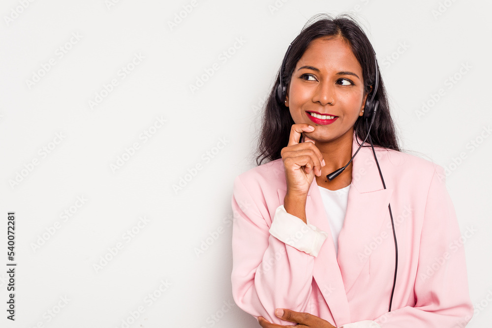 Telemarketer Indian woman working with a headset isolated on white background relaxed thinking about something looking at a copy space. Telemarketer Indian woman working with a headset isolated on white background relaxed thinking about something looking at a copy space.