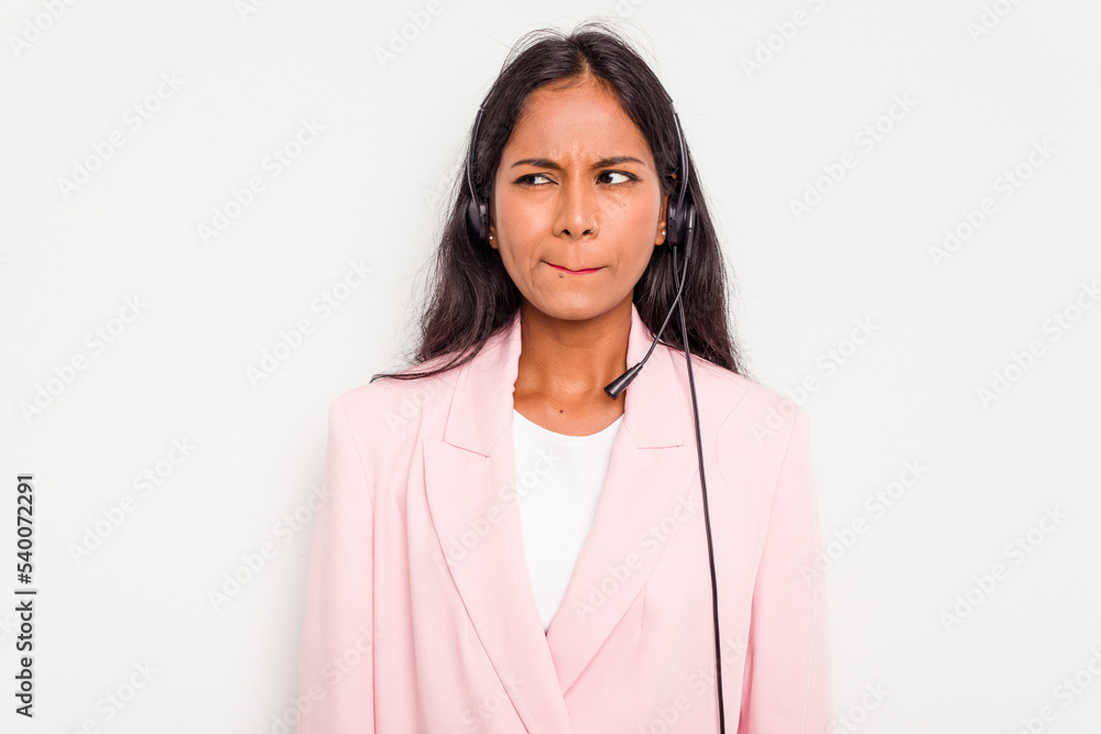Telemarketer Indian woman working with a headset isolated on white background confused, feels doubtful and unsure.