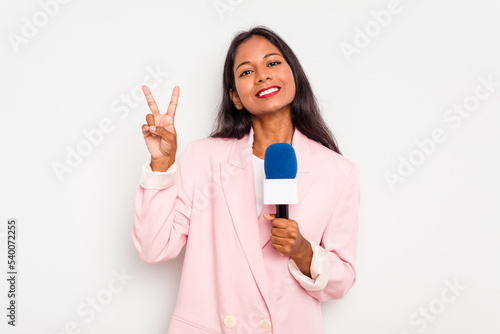 Young TV presenter indian woman isolated on white background joyful and carefree showing a peace symbol with fingers.