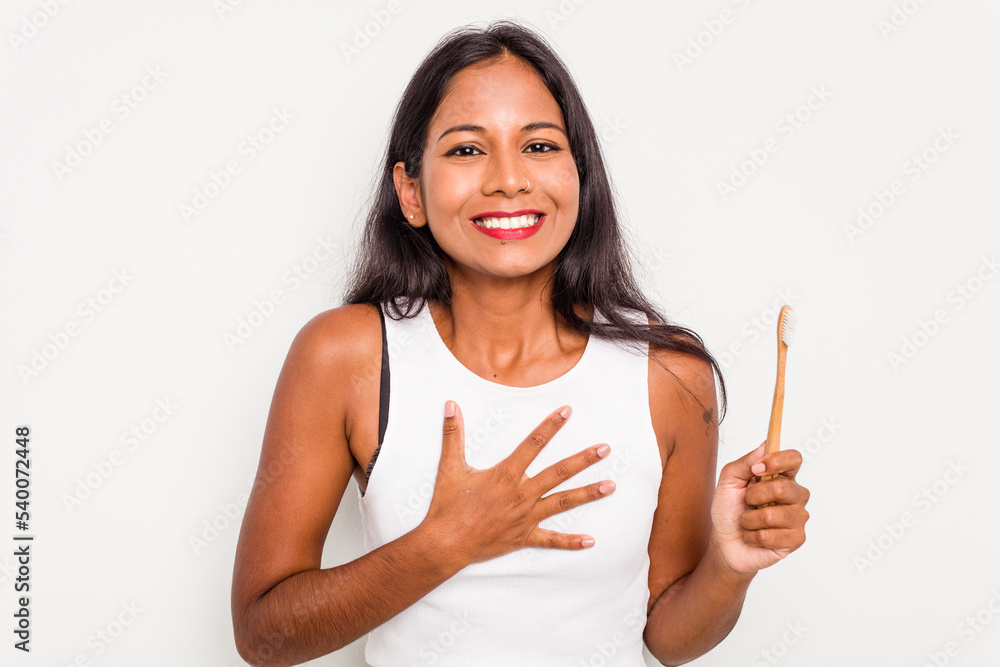 Young Indian woman brushing teeth isolated on white background laughs out loudly keeping hand on chest.