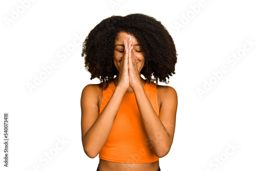 Young African American woman isolated holding hands in pray near mouth, feels confident. photo