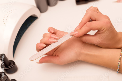 A woman makes a beautiful manicure for herself, saws nails with a nail file photo