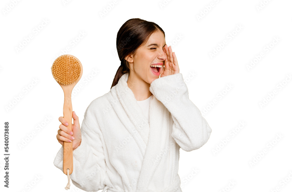 Young caucasian woman holding a shower brush isolated shouting and holding palm near opened mouth. Young caucasian woman holding a shower brush isolated shouting and holding palm near opened mouth.