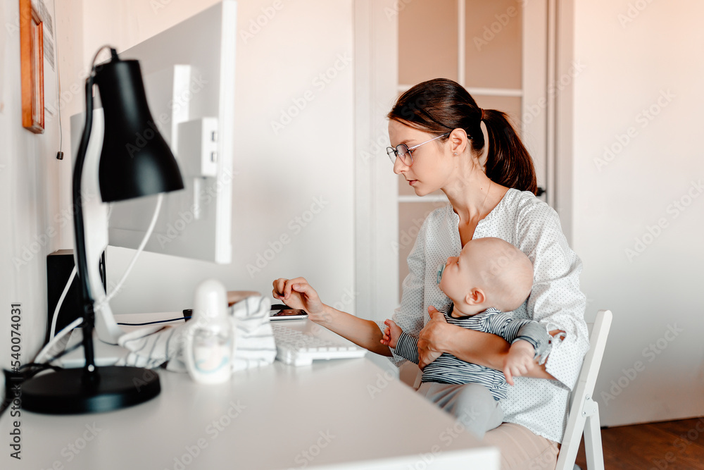 Mother working on computer with baby in hands. Working mother with kid. Mother working on computer with baby in hands. Working mother with kid.
